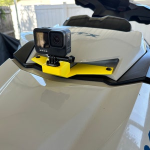 Op de afbeelding: Een zwarte GoPro-camera gemonteerd op een gele beugel die aan de voorkant van een witte jetski is bevestigd.