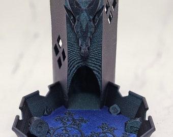 Könnte beinhalten: Ein schwarzer 3D-gedruckter Würfelturm mit einem Schädel- und Horn-Design. Der Turm steht auf einem schwarzen und blauen Würfeltablett mit einem wirbelnden Muster.