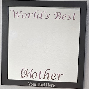 May include: A black framed mirror with the text "World's Best Mother" in pink cursive lettering. The text "Your Text Here" is printed in silver below the cursive lettering.