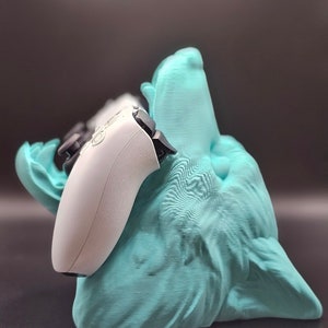 May include: A teal blue 3D printed wolf head with a white video game controller resting in its mouth.