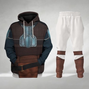 Può includere: Una felpa con cappuccio marrone e blu con un design a placca toracica argentata e pantaloni della tuta abbinati marrone e bianco con accenti marroni.