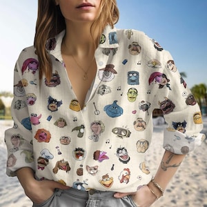 以下が含まれることがあります： クリーム色のボタンダウンシャツ。カラフルな漫画のキャラクターの顔が繰り返し描かれたパターンです。長袖シャツは襟付きで、軽くてカジュアルウェアに適した生地で作られています。