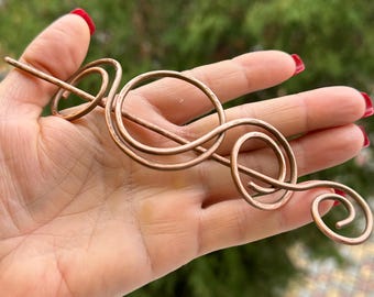 May include: A copper wire hair stick with a decorative swirl design.