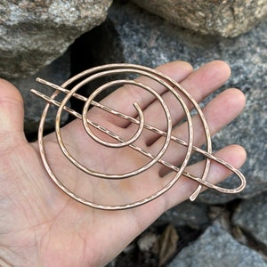 May include: A copper hair comb with a spiral design. The comb is hammered for a textured look.