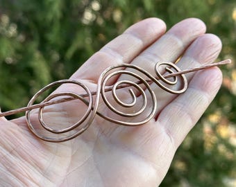 May include: A copper hair stick with a spiral design. The stick is about 6 inches long and has a hammered finish.