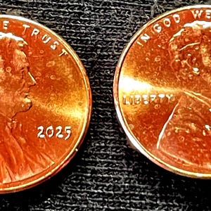 May include: Two copper-coloured United States pennies. Each coin features a profile of Abraham Lincoln, the word "LIBERTY", the year "2025", and the phrase "IN GOD WE TRUST".
