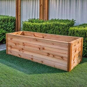 Peut inclure: Un bac à plantes rectangulaire en bois brun clair. Le bac est vide et repose sur un lit d'herbe artificielle verte. La boîte est construite avec des planches de bois horizontales.