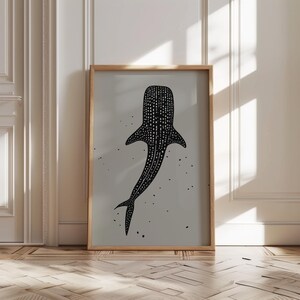 Minimalist illustration wall art depicting a whale shark swimming in the ocean in an elegant manner, the shark is drawn in a black color with white dots and the background is a beige color with black ink spots