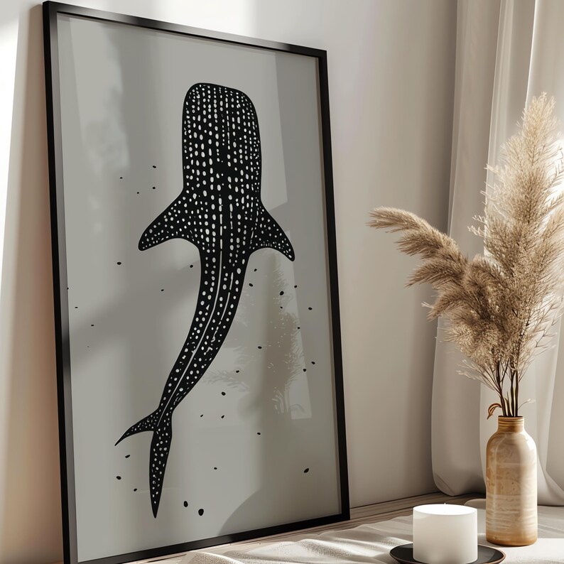 Minimalist illustration print depicting a whale shark swimming in the ocean in an elegant manner, the shark is drawn in a black color with white dots and the background is a beige color with black ink spots, it is hanging in a modern kitchen