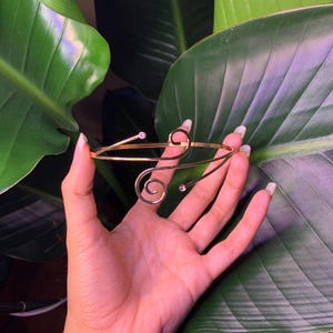 Peut inclure: Un bracelet dor&eacute; avec un design d&eacute;licat en spirale et deux petits strass transparents.