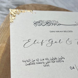 May include: A white card with gold accents and the text "DINI NIKAH BELGESI" in black. The text "Elif G&uuml;l &" is written in cursive below the title. The card also includes a quote in Arabic script.