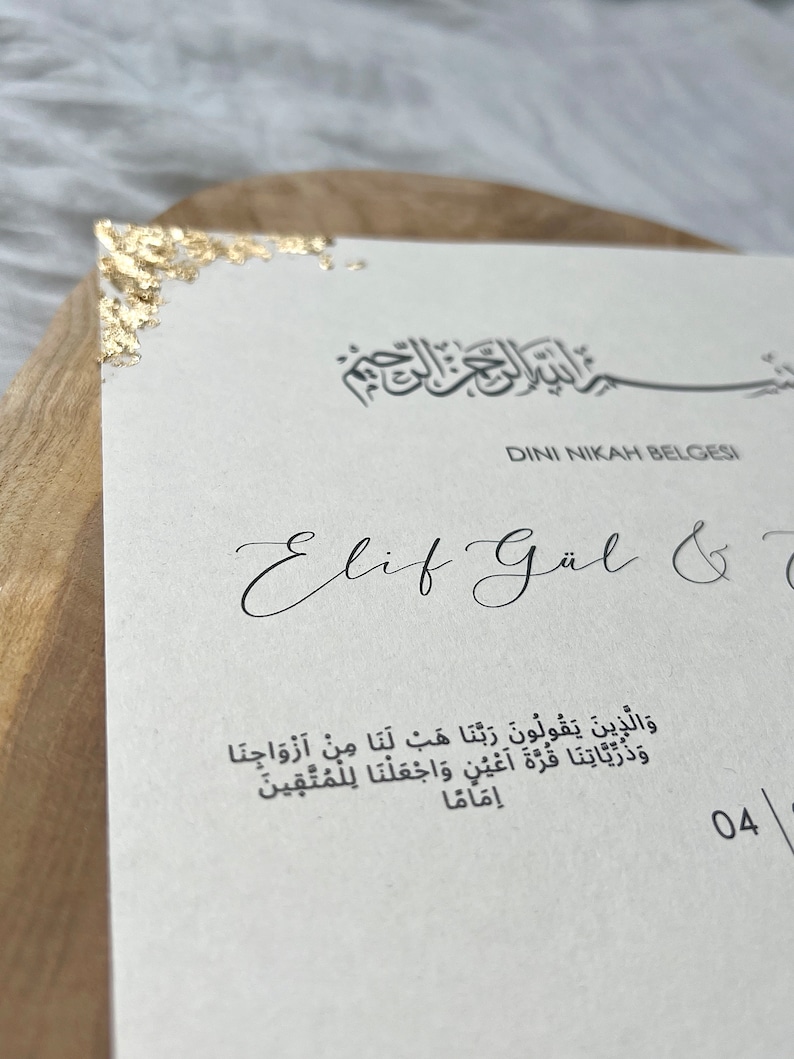May include: A white card with gold accents and the text "DINI NIKAH BELGESI" in black. The text "Elif G&uuml;l &" is written in cursive below the title. The card also includes a quote in Arabic script.