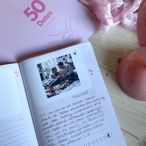 May include: A white journal with a pink cover that says "50 Dates to remember". The journal has a photo of a couple on a date and a handwritten entry that says "14.02.2025 es war so ein schöner Abend! Alex & ich haben als erstes die Wohnung und das Setting vorbereitet & sind anschließend einkaufen gegangen. Wir haben uns viel mehr unterhalten, als wir es sonst im Restaurant tun. Anschließend haben wir uns dazu entschieden einen Film schauen :)♡".