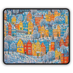 May include: A colorful mousepad featuring a winter village scene. The illustration depicts houses in shades of blue, yellow, orange, and red, covered in snow. Snow-covered trees and a winding road add to the wintery landscape.