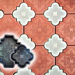 Puede incluir: Primer plano de un diseño de pavimento estampado en tonos coral, blanco y gris. Dos moldes de color gris oscuro están en primer plano, mostrando los intrincados detalles florales y geométricos del pavimento. Los adoquines están dispuestos en un patrón repetitivo.