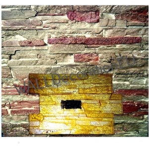 May include: A close-up of a textured stone wall with a yellow, textured, rectangular panel in the center. The panel has a black rectangular opening in the center.