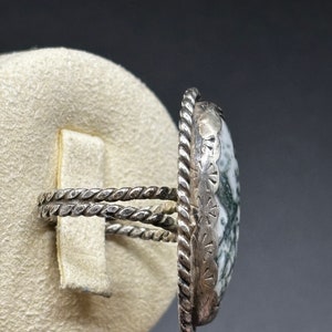 May include: A silver ring with a green and white agate stone set in a twisted silver band.