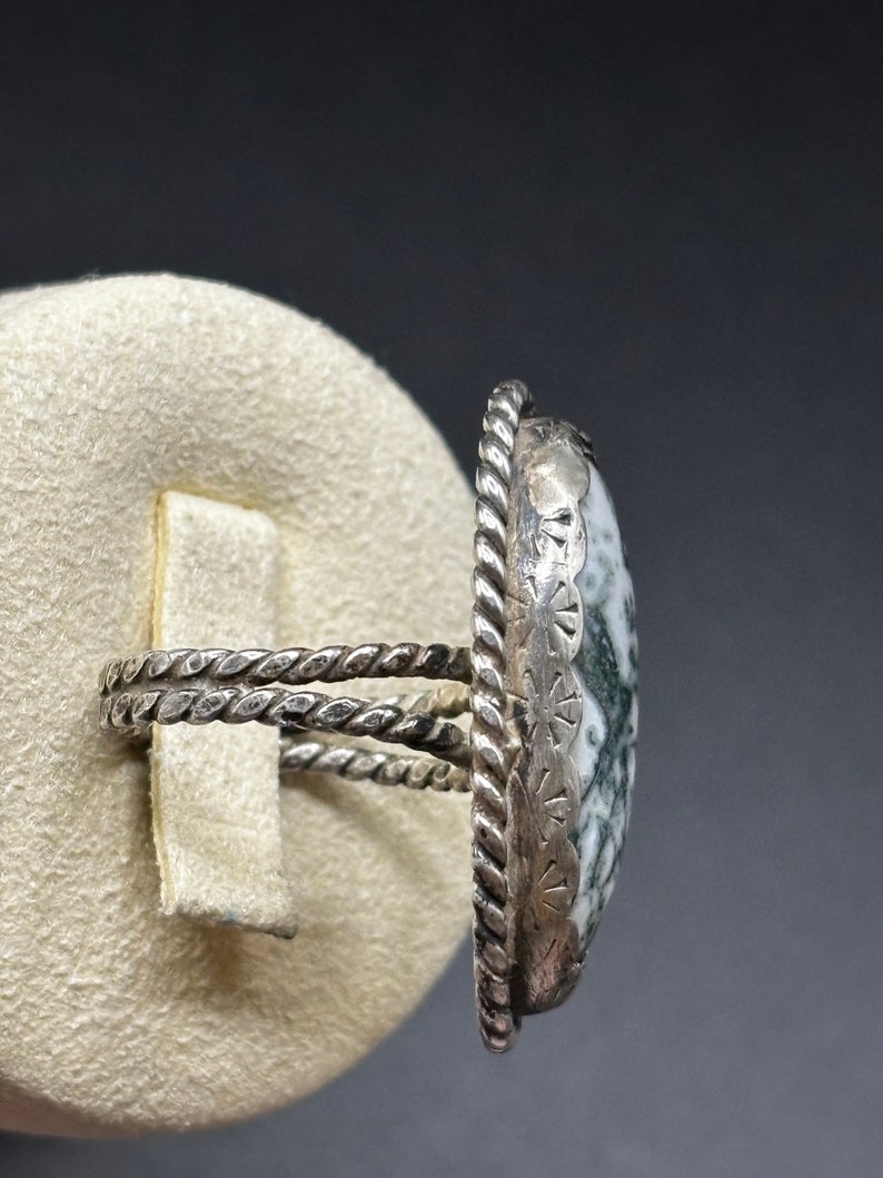 May include: A silver ring with a green and white agate stone set in a twisted silver band.
