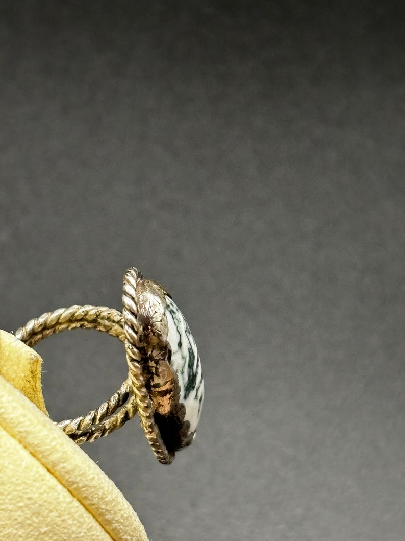 May include: A silver ring with a green and white agate stone. The ring is set in a twisted silver band.