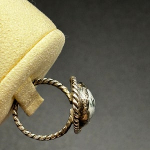 May include: A silver ring with a white and green stone set in a twisted band.