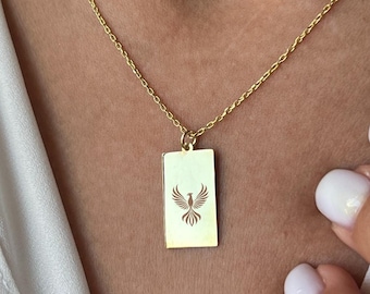 May include: A gold chain necklace with a rectangular pendant featuring a cutout design of a bird in flight.
