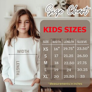 May include: A white sweatshirt with a size chart labeled "KIDS SIZES" in red. The chart lists sizes XS to XL with measurements in inches for width, length, and sleeve. The image also shows a young person wearing the sweatshirt.