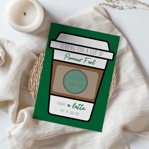 May include: A green card with a cartoon coffee cup illustration. The text on the card reads "Sending you a cup of Pioneer Fuel. Place gift card here. Thanks a latte for all you do!"