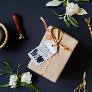May include: A brown gift box with a gold ribbon and a white gift tag that says "Our Big Husband Anniversary" with a cartoon illustration of a group of men in suits.