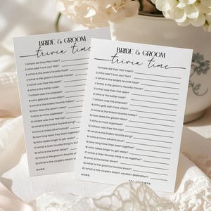 Pode incluir: Dois cartões retangulares de papel branco com texto em preto intitulado Bride & Groom Trivia Time. Cada cartão lista vinte perguntas numeradas sobre um casal com linhas em branco para respostas e um espaço para um nome na parte inferior.