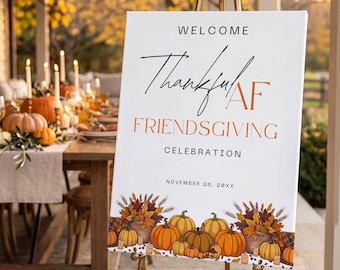 Könnte beinhalten: Ein weißes rechteckiges Willkommensschild auf einer goldenen Metallstaffelei mit dem schwarzen und orangefarbenen Text Welcome Thankful AF Friendsgiving Celebration November 28, 20XX, und einer bunten Illustration von Kürbissen und Herbstlaub.