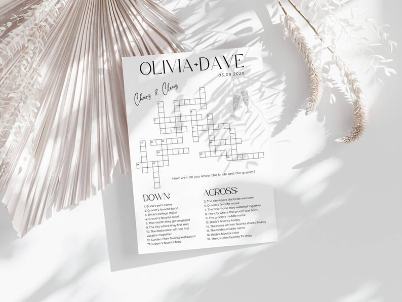 K&ouml;nnte beinhalten: Ein wei&szlig;es Hochzeitskreuzwortr&auml;tsel mit den Namen Olivia und Dave und dem Datum 05.09.202x. Das R&auml;tsel enth&auml;lt Hinweise f&uuml;r die G&auml;ste, um mehr &uuml;ber das Brautpaar zu erfahren. Das Papier liegt auf einer wei&szlig;en Oberfl&auml;che mit Schatten.