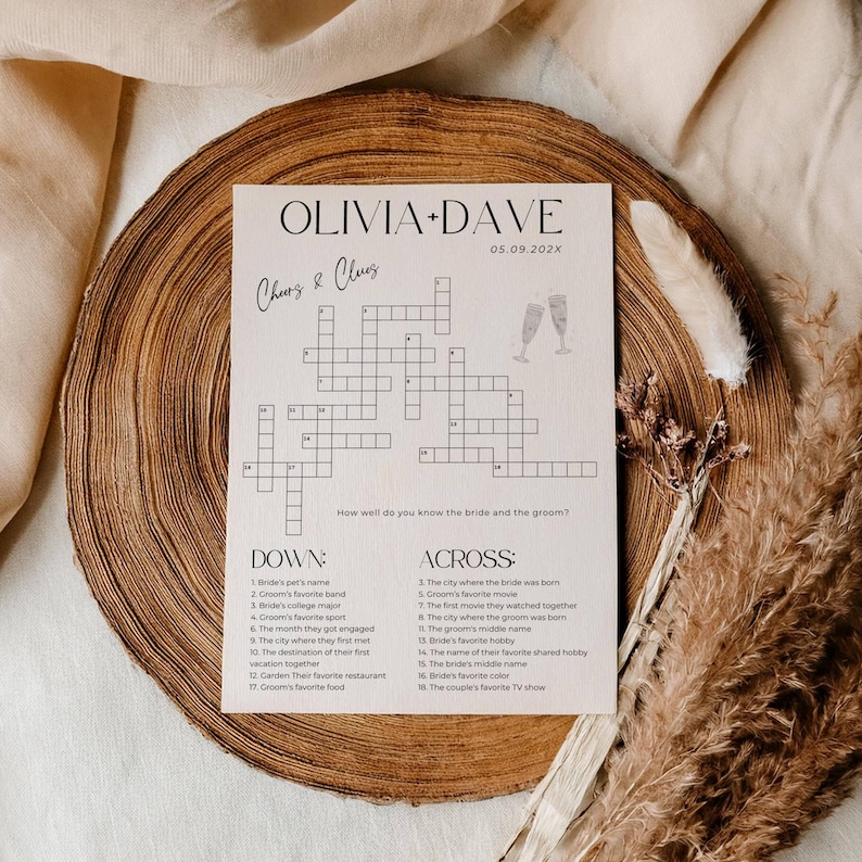 K&ouml;nnte beinhalten: Ein Hochzeits-Kreuzwortr&auml;tsel mit den Namen "OLIVIA + DAVE" und dem Datum "05.09.202X" oben. Das R&auml;tsel enth&auml;lt Hinweise auf Braut und Br&auml;utigam, mit Champagnergl&auml;sern illustriert. Das R&auml;tsel befindet sich auf hellem Papier.