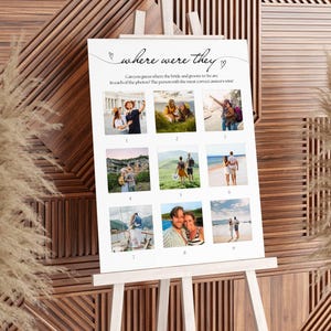 May include: A white sign on a wooden easel with the text "where were they" and nine small photos. The sign is for a wedding game. The background is a wooden wall with dried plants.