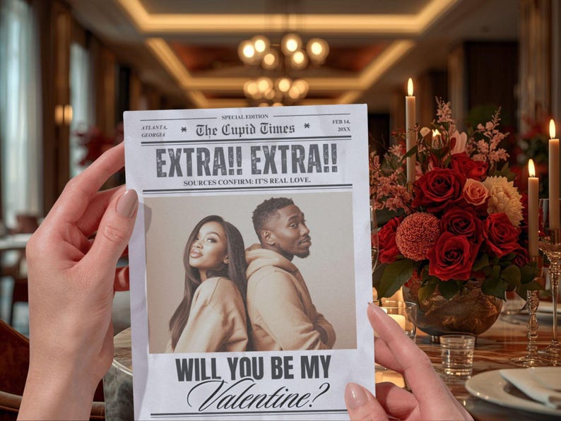 May include: A newspaper with the headline "EXTRA!! EXTRA!!" and the text "WILL YOU BE MY Valentine?" is held in front of a floral arrangement. The newspaper features a photo of a couple. The scene is set on a table with candles.