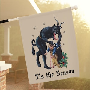 May include: A beige flag with a vintage illustration of a black Krampus figure with a child. The Krampus has a long tongue and is holding the child. The flag has the text "Tis the Season" in a gothic font, with snowflakes.