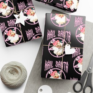 May include: Black and pink wrapping paper with a repeating pattern of a cartoon Santa Claus in a pentagram with the text "Hail Santa".