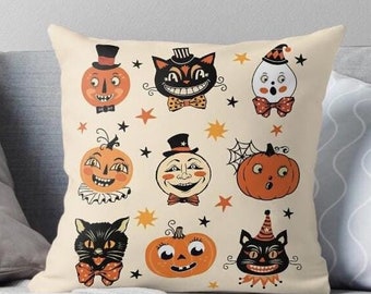 May include: A cream-colored pillow with a Halloween theme. The pillow features a variety of vintage-style illustrations, including pumpkins, cats, and ghosts. The illustrations are in shades of orange, black, and white.