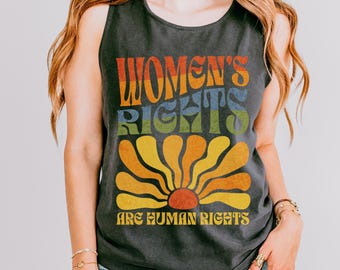 May include: A black tank top with a rainbow-colored graphic that says "Women's Rights Are Human Rights". The graphic features a stylized sun with a flower-like design.