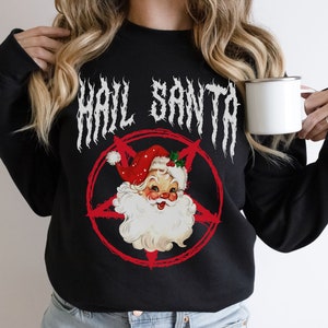 May include: Black sweatshirt with a white graphic of a cartoon Santa Claus with a pentagram behind him. The text "Hail Santa" is written in a metal font above the graphic.