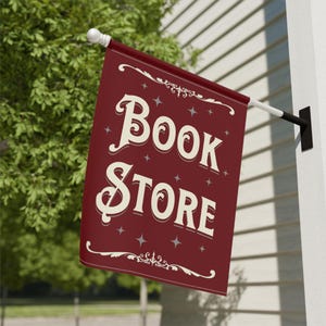 May include: A red and white flag with the text "Book Store" in a vintage font. The flag is hanging from a pole outside of a building.