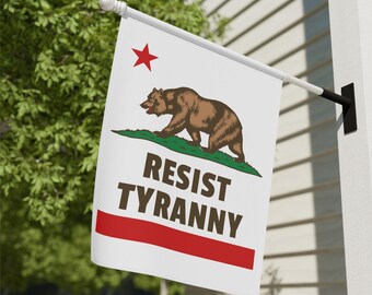 May include: A white flag with the California state bear and a red star, with the words "RESIST TYRANNY" in brown. The flag has a red stripe at the bottom and is mounted on a white pole.