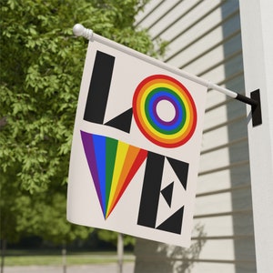 May include: A white flag with the word "LOVE" in black letters. The "O" is a rainbow circle with a smaller white circle in the center. The "V" is a rainbow triangle.