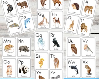 May include: A set of alphabet flashcards featuring animals and their names in German. Each card has a letter, an animal illustration, and the animal's name written below.