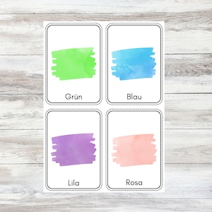 May include: Four color cards with watercolor swatches and German words for the colors: Gr&uuml;n (green), Blau (blue), Lila (purple), and Rosa (pink).