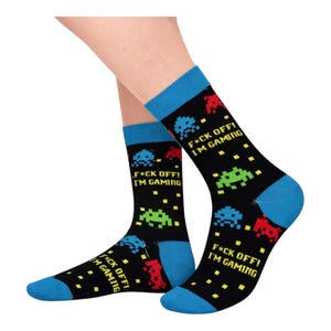 May include: Black socks with blue cuffs and toes, decorated with pixelated alien designs in red, green, and blue. The text "F*CK OFF! I'M GAMING" is printed on the socks, suitable for gamers.