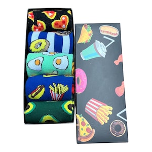 May include: A set of six pairs of colourful socks in a black box. The socks feature various food designs, including pizza, doughnuts, eggs, hot dogs, chips, and avocados.