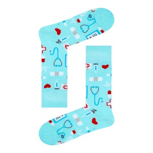 May include: A pair of light blue socks patterned with medical symbols. The design includes stethoscopes, bandages, syringes, and red hearts. These socks are intended for wear on the feet.