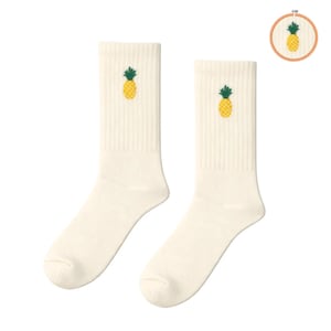 May include: A pair of off-white ribbed crew socks featuring a small embroidered pineapple motif with a yellow body and green leaves. The pineapple design is also shown in a circular wooden embroidery hoop in the upper right corner of the image.