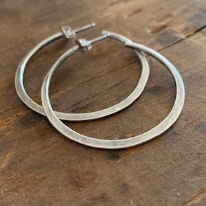 May include: A pair of silver hoop earrings with a brushed finish.