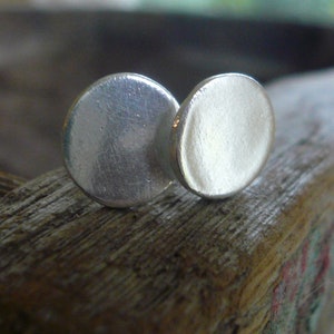 May include: A pair of silver earrings, each with a round, smooth, and slightly domed shape.